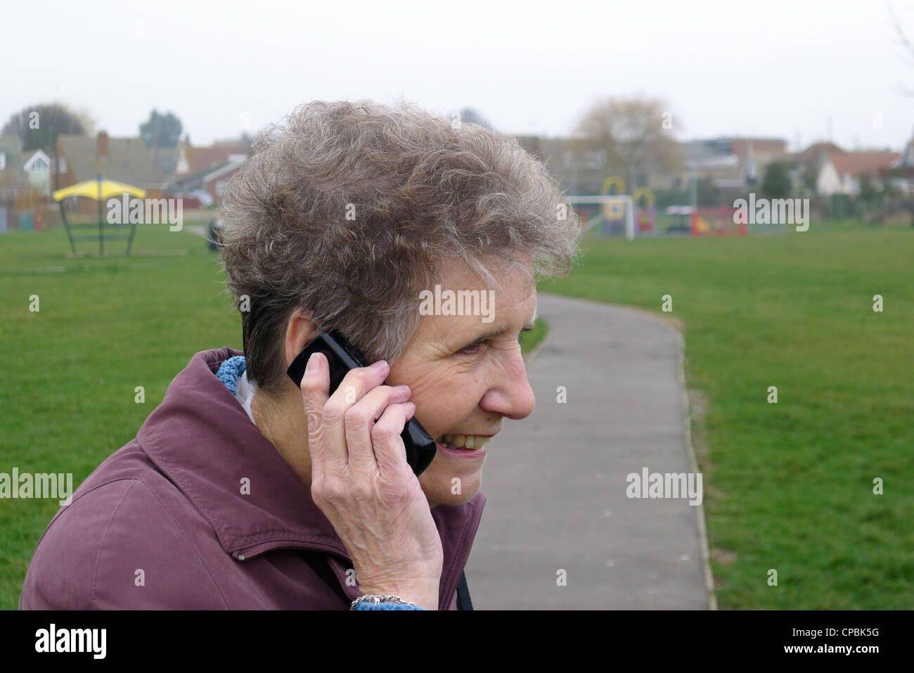 Eine ältere Frau lächelnd und telefonieren mit einem Handy Stockfoto