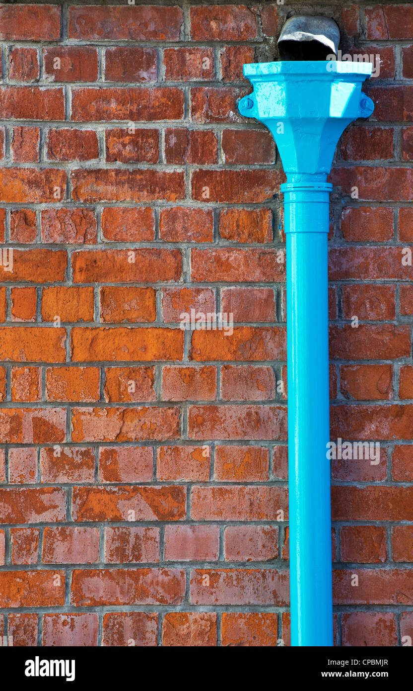 Blaue Fallrohr gegen einen roten Backsteinmauer. England Stockfoto