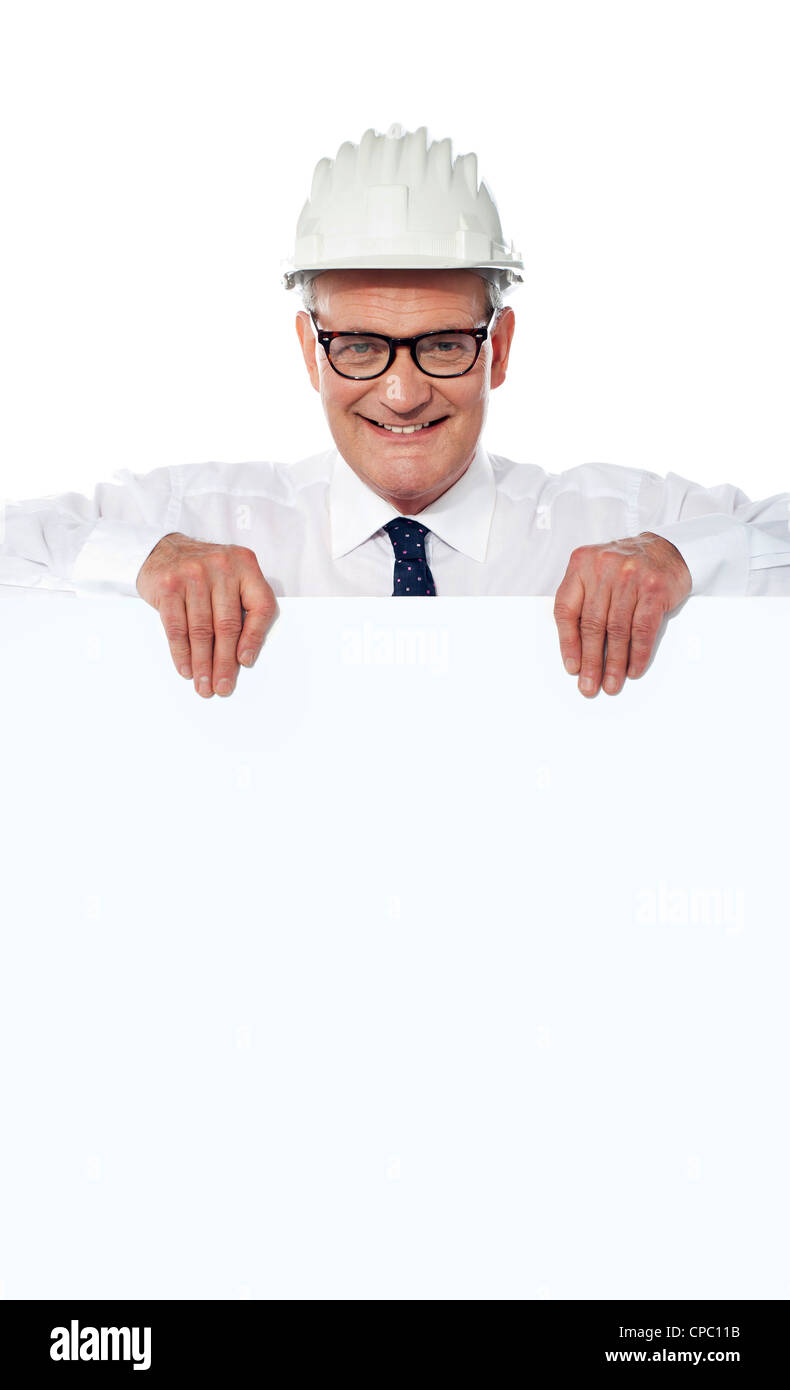 Foto von smart senior Architekt im Helm hält leere Plakat über weißem Hintergrund Stockfoto