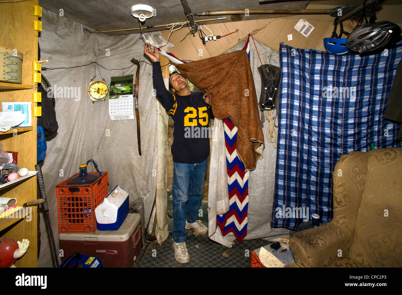 Eine militärische Veteran betritt seine provisorische Zuflucht unter Obdachlosen Bewohner von einem primitiven Outdoor-Lager in der Wüste. Stockfoto