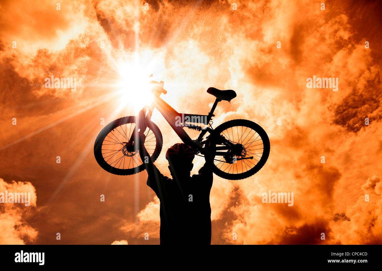 Die Silhouette der Mountainbiker angehoben Fahrrad mit Sonnenuntergang und Cloud Hintergrund Stockfoto