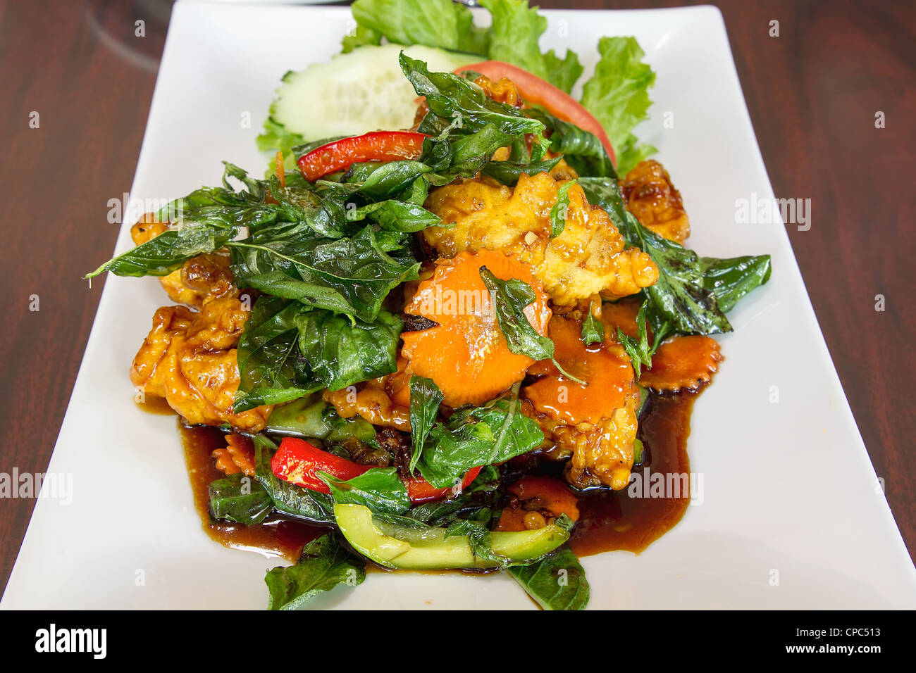 Thai knusprig gebratenes Huhn mit Basilikum Blätter Paprika Gurke Tomate Schüssel vertikal Stockfoto