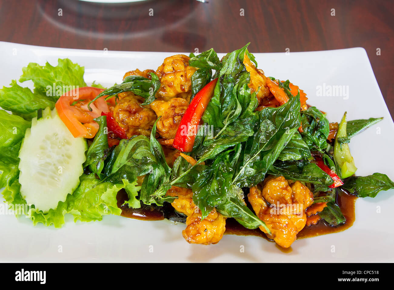 Thai knusprig gebratenes Huhn mit Basilikum Blätter Paprika Gurke Tomaten Gericht Stockfoto