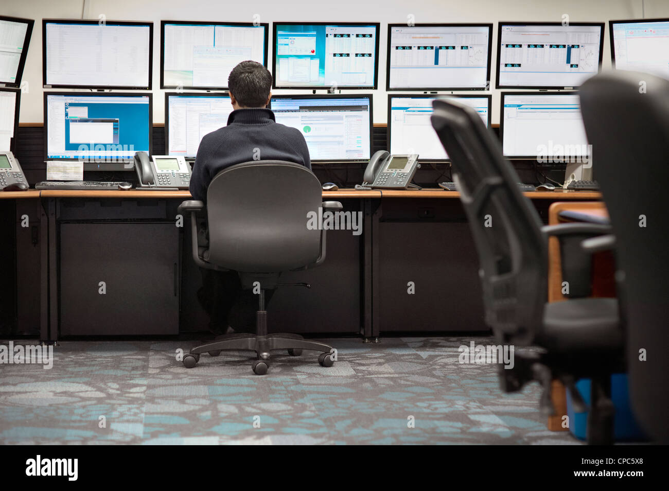 Ein Mann betrachtet man mehrere Handel Bildschirme an seinem Schreibtisch. Stockfoto