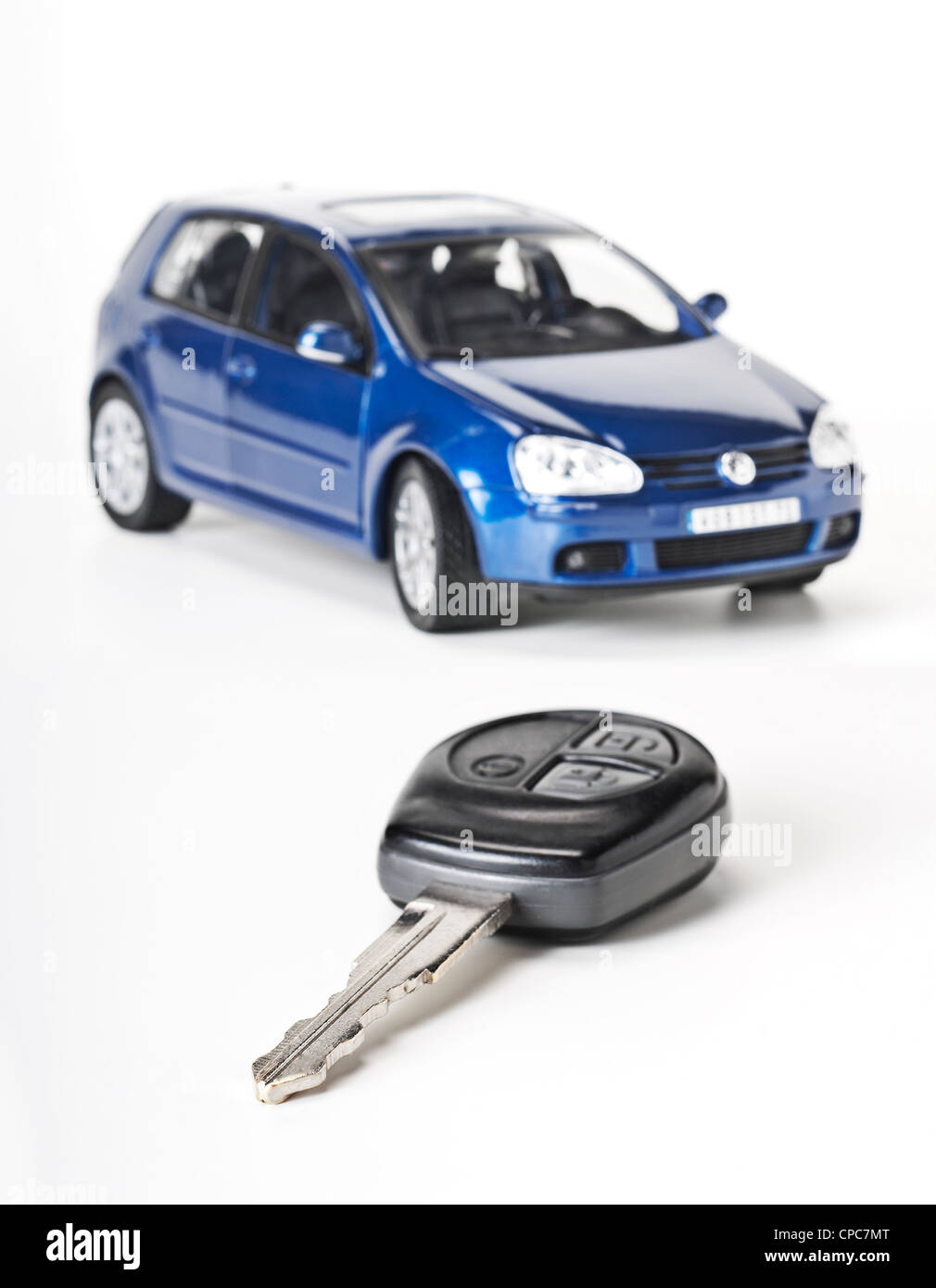 Autoschlüssel als eine Nahaufnahme und ein blaues Auto im Hintergrund. Stockfoto