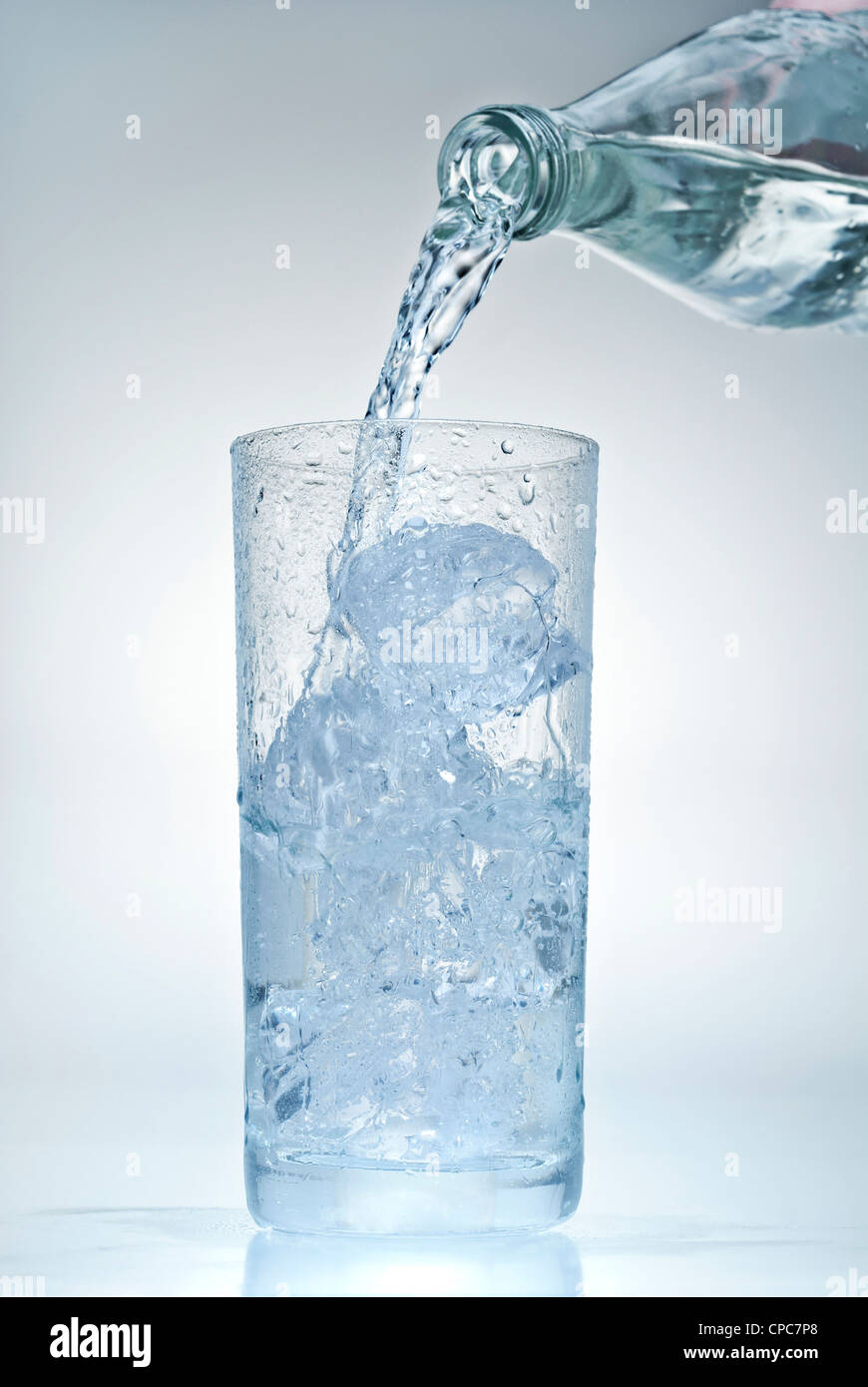 Mineralwasser wird in ein Glas mit Eiswürfel gegossen. Stockfoto