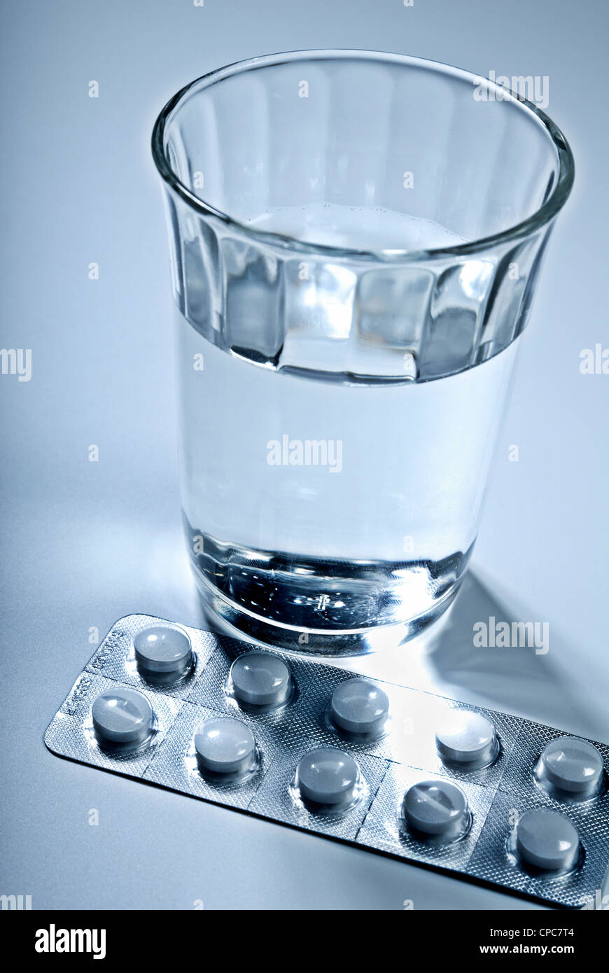 Tabletten in einer Blisterverpackung und ein Glas Wasser. Stockfoto