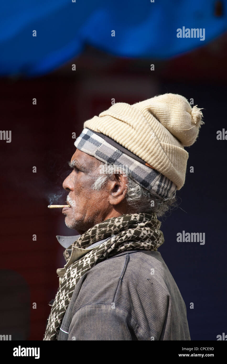 Ein asiatischer indischen Mann gekleidet für die Kälte und Rauchen auf dunklem Hintergrund Stockfoto