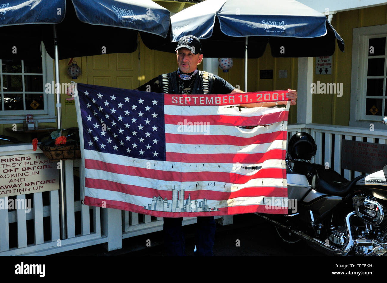 Ein Biker hält eine zerrissene amerikanische Flagge enthält eine Bild von den Twin Towers und "11. September 2001" Stockfoto