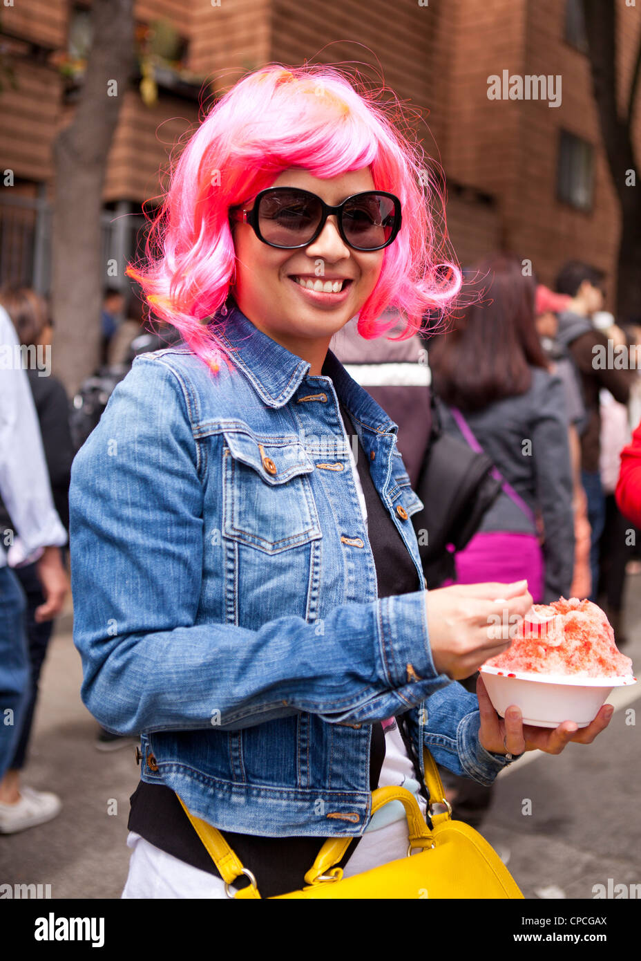 Eine asiatische Frau trägt eine rosa Perücke bei einem Outdoor-festival Stockfoto