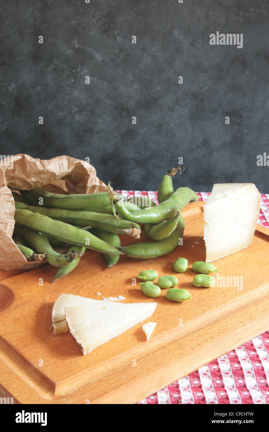 Schneidbrett aus Holz mit dicken Bohnen und Schafskäse mit textfreiraum auf schwarzem Hintergrund Stockfoto