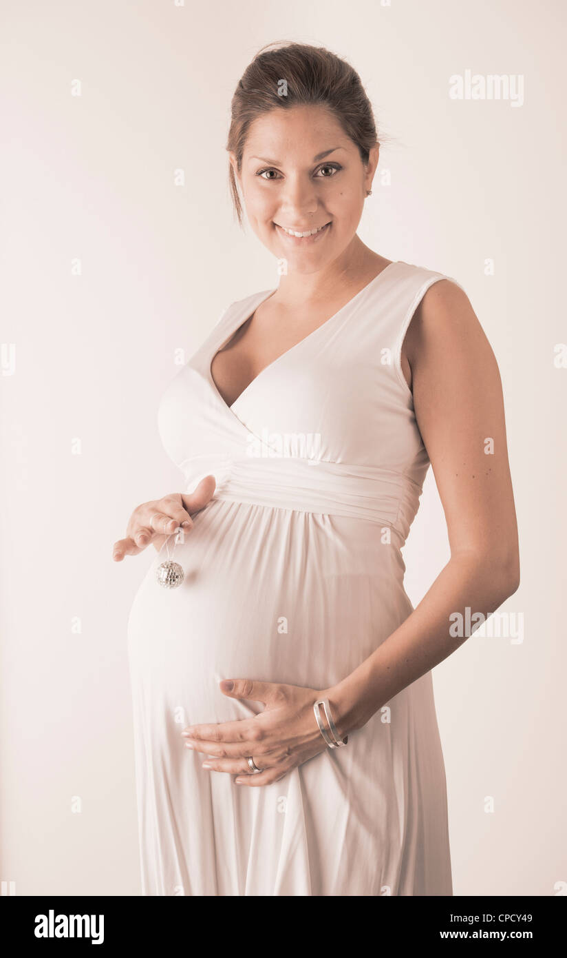 Schwangere Frau an Hand mit Miniatur-Disco-Kugel auf dem Bauch Stockfoto
