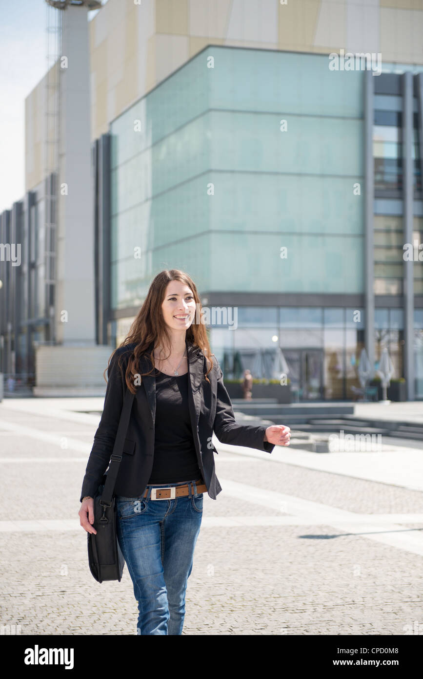 Junge lächelnde Frau in Eile - Fußgängerzone mit Notebook Tasche Stockfoto