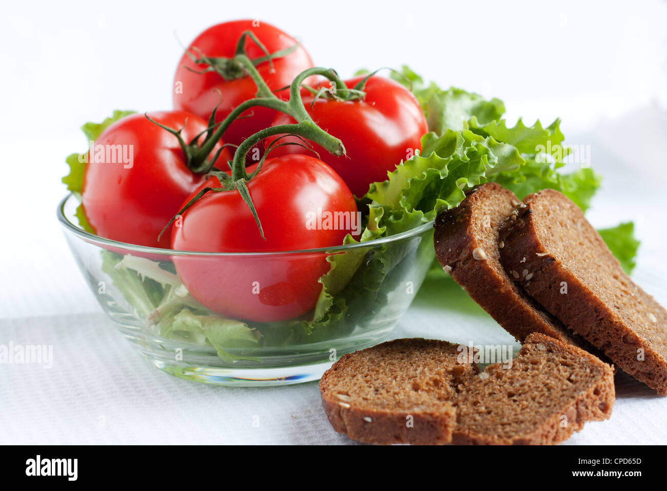 Ganze Tomaten und Salat in eine Salat-Schüssel und Brot-Scheiben Stockfoto
