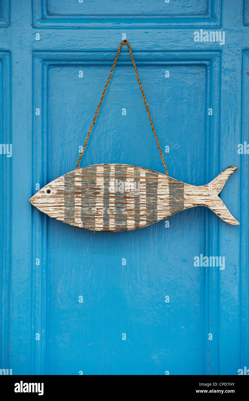 Hölzerne Fisch Ornament blaue Tür hängen. Clovelly, Devon, England Stockfoto