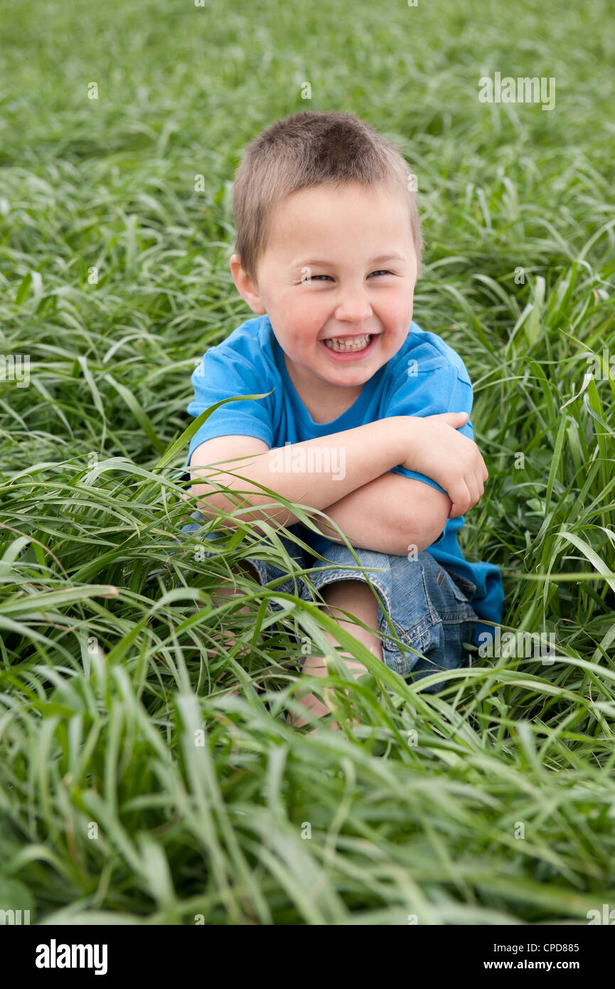 lächelnde junge sitzt auf Wiese Stockfoto