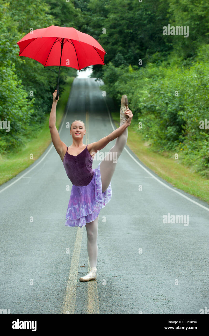 Kaukasische Ballerina tanzen auf remote-Straße mit Regenschirm Stockfoto