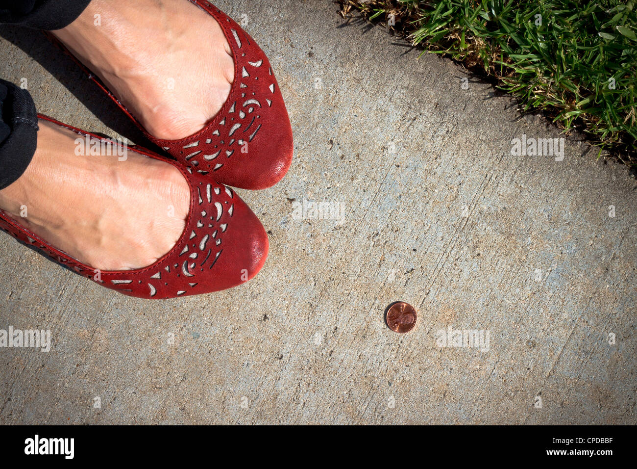 Eine Mädchen mit roten Schuhen findet einen Penny auf dem Bürgersteig. Holen Sie es und Sie haben viel Glück ganztägig! Stockfoto