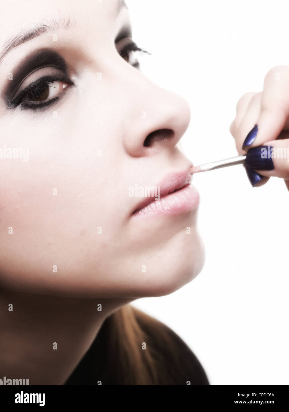 schöne junge Brünette Frau Lippenstift auftragen, mit einem Pinsel isoliert auf weiss Stockfoto