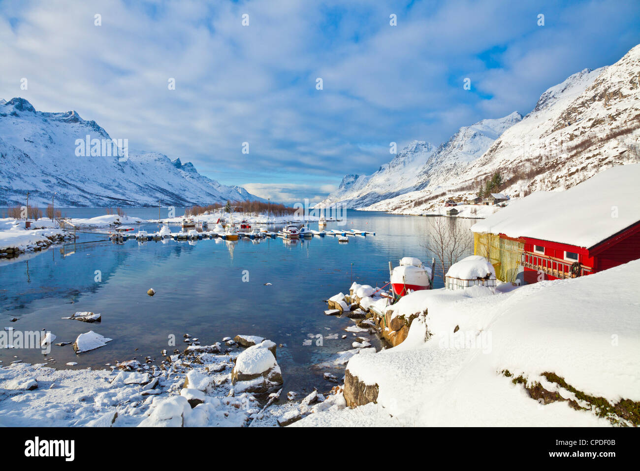 Schneebedeckte Berge, Bootshaus und Liegeplätzen im norwegischen Fjord Dorf von Ersfjord, Kvaloya Insel, Troms, Norwegen Stockfoto