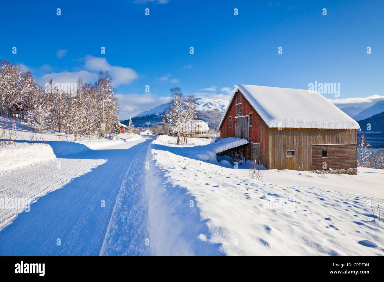 Schneebedeckte Straße, Scheune und Chalets im norwegischen Dorf von Laukslett, Troms, Nord-Norwegen, Skandinavien, Europa Stockfoto