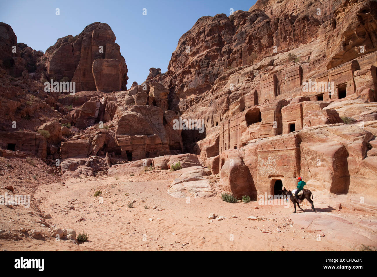 Kind reiten einen Esel vor der Höhle Wohnungen in Petra, UNESCO-Weltkulturerbe, Jordanien, Naher Osten Stockfoto
