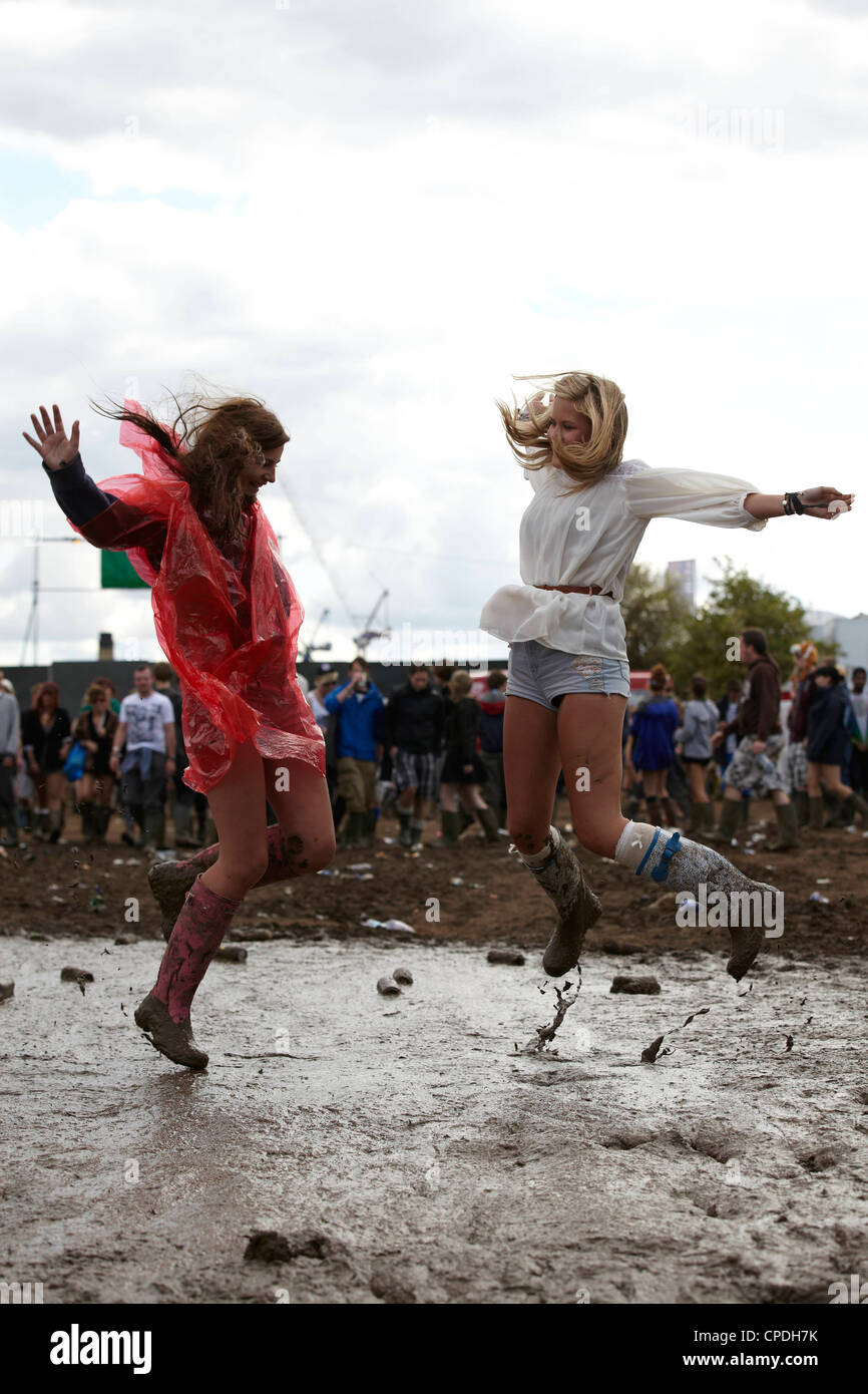 Zwei Mädchen springen und spielen im Schlamm auf einem Musikfestival Stockfoto