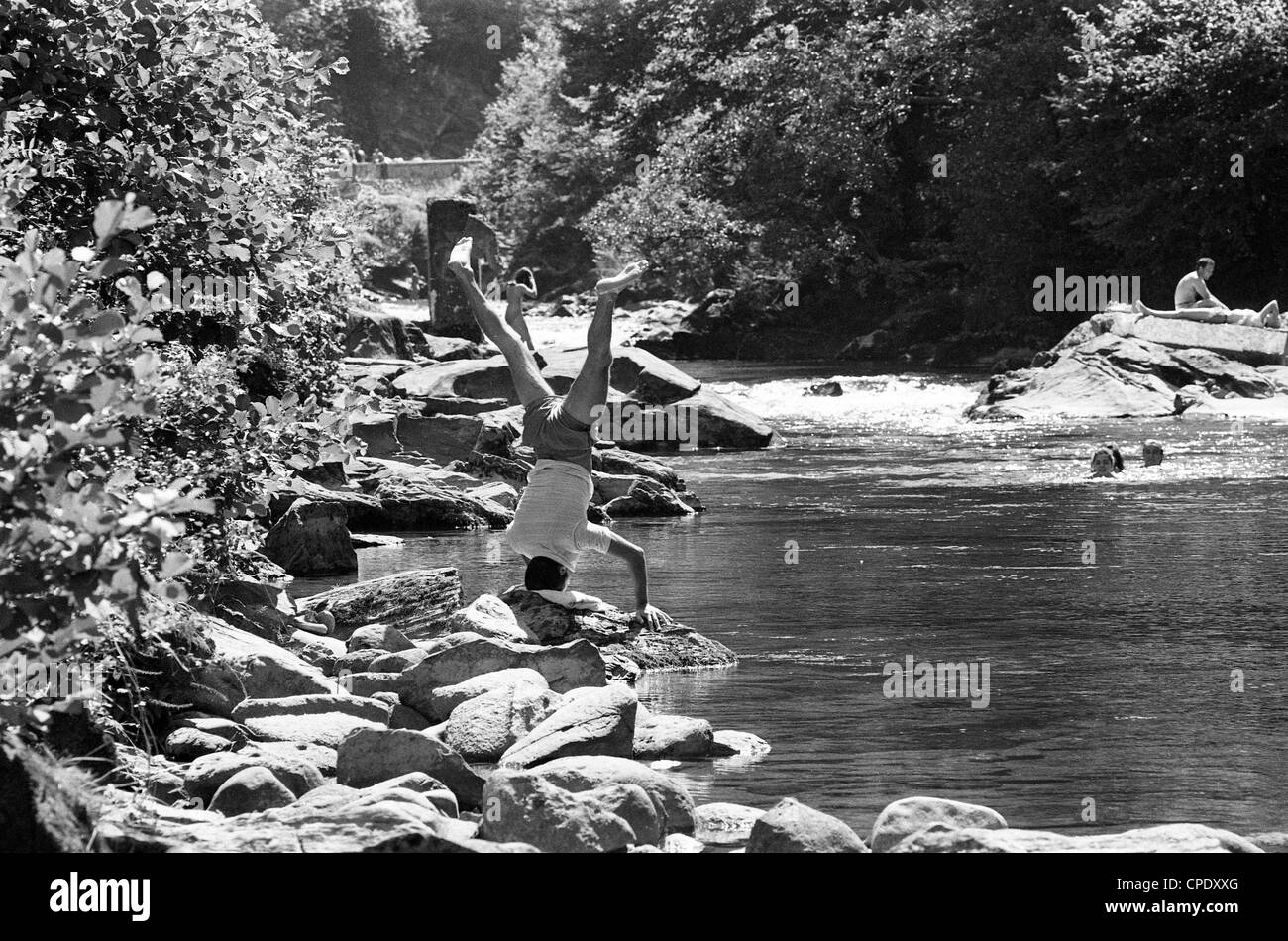 Mann, der Yoga-Handstand auf Felsen am Fluss Salat bei Seix in der Midi Pyrénées France 1990 macht. Kopfstand Yoga Stretch Position Klasse im Freien Französisch Stockfoto