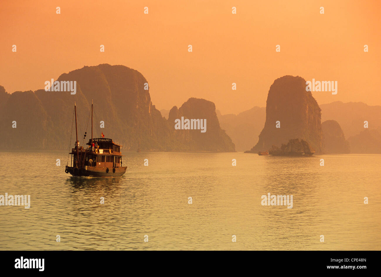 Traditionelles Boot segeln durch Kalkstein Schären bei Sonnenuntergang, Ha Long Bay, nordöstlich, Indochina, Vietnam, Südostasien Stockfoto