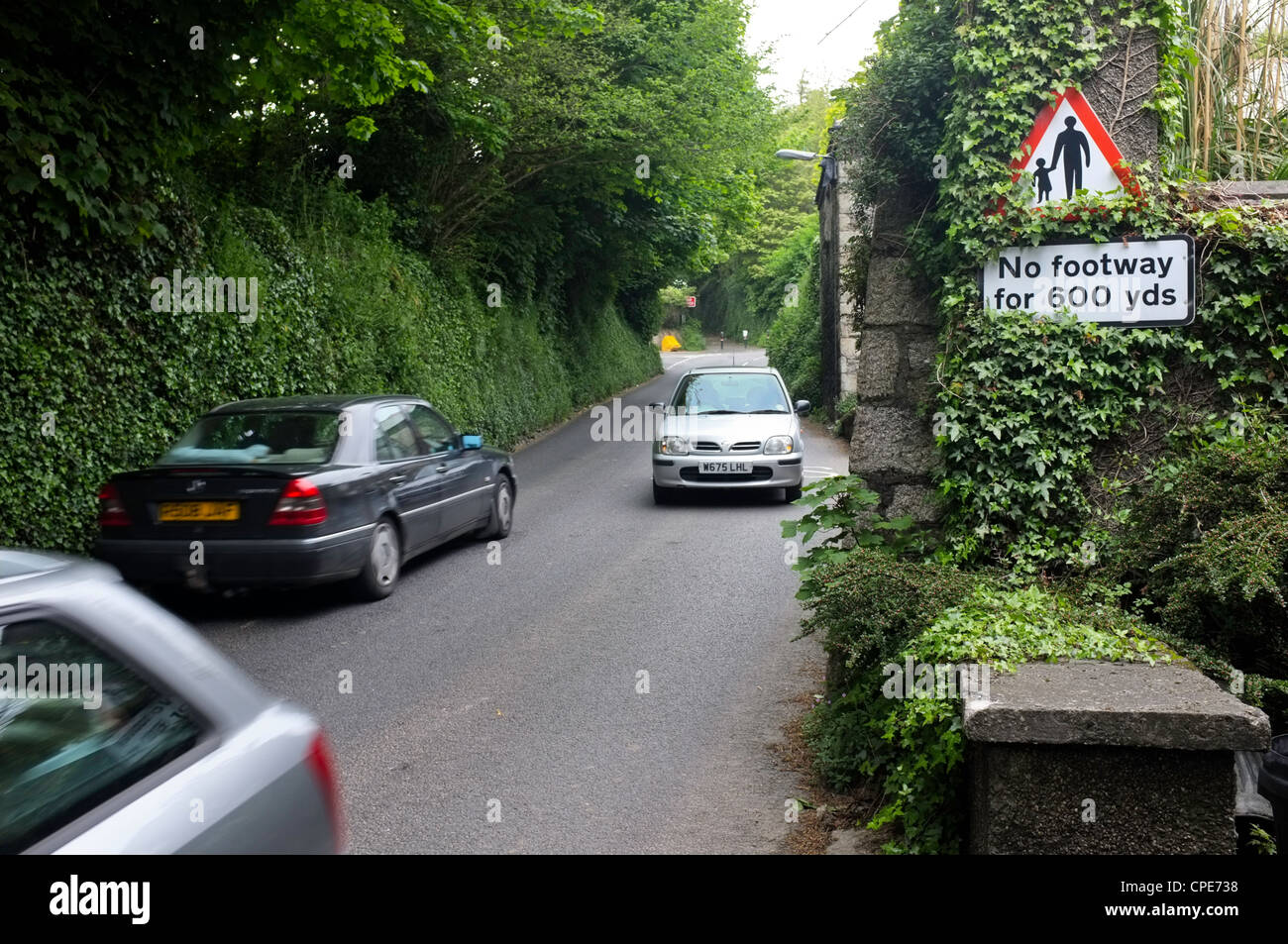 Autos auf einer schmalen Straße ohne Bürgersteig für Fußgänger Stockfoto