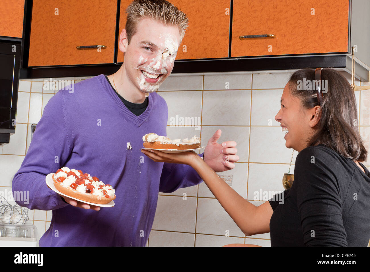 Junges Paar erst eine Sahnetorte zu kämpfen, in der Küche Stockfoto