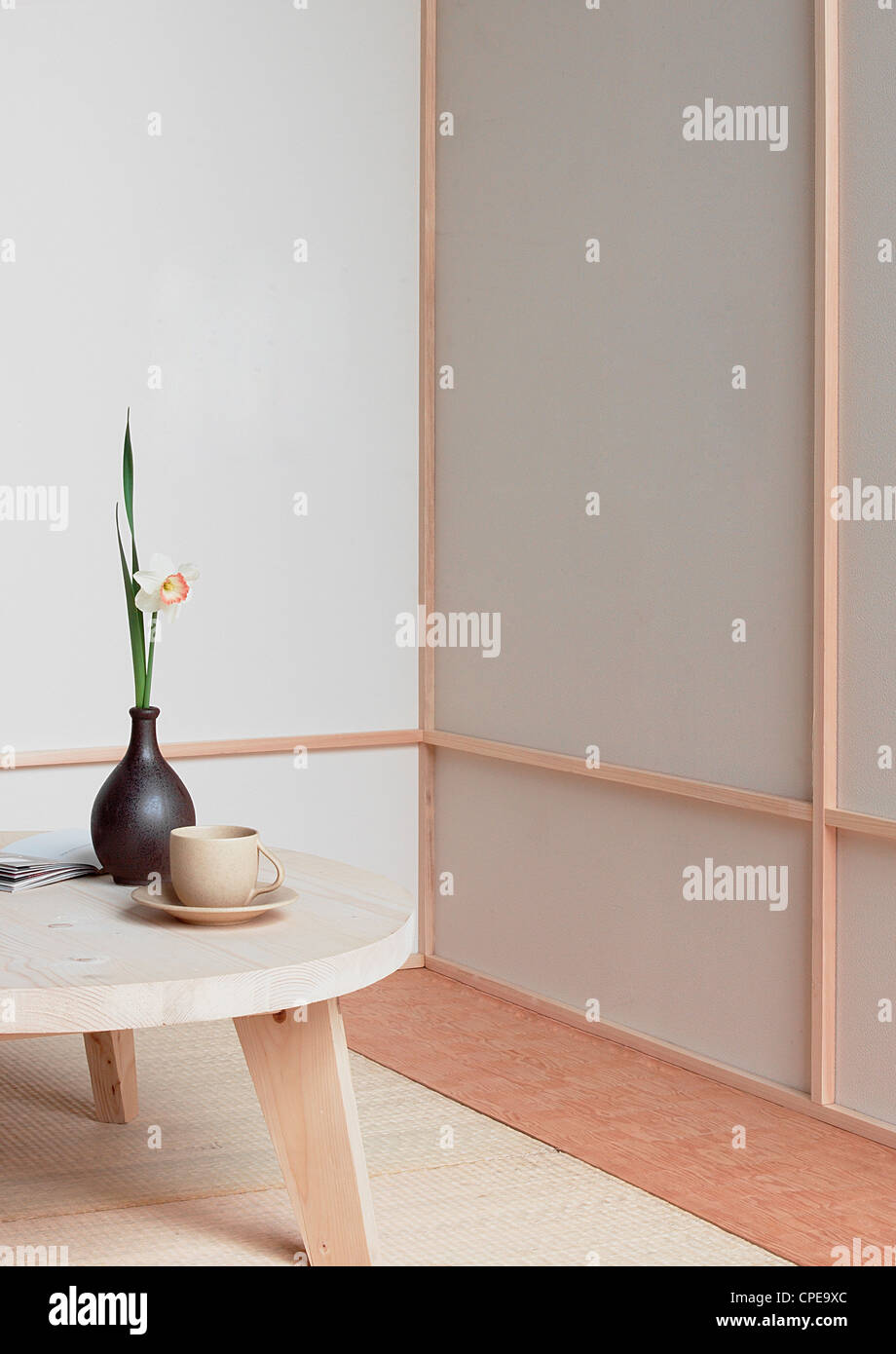 Holztisch mit Teetasse und Blumenvase Stockfoto