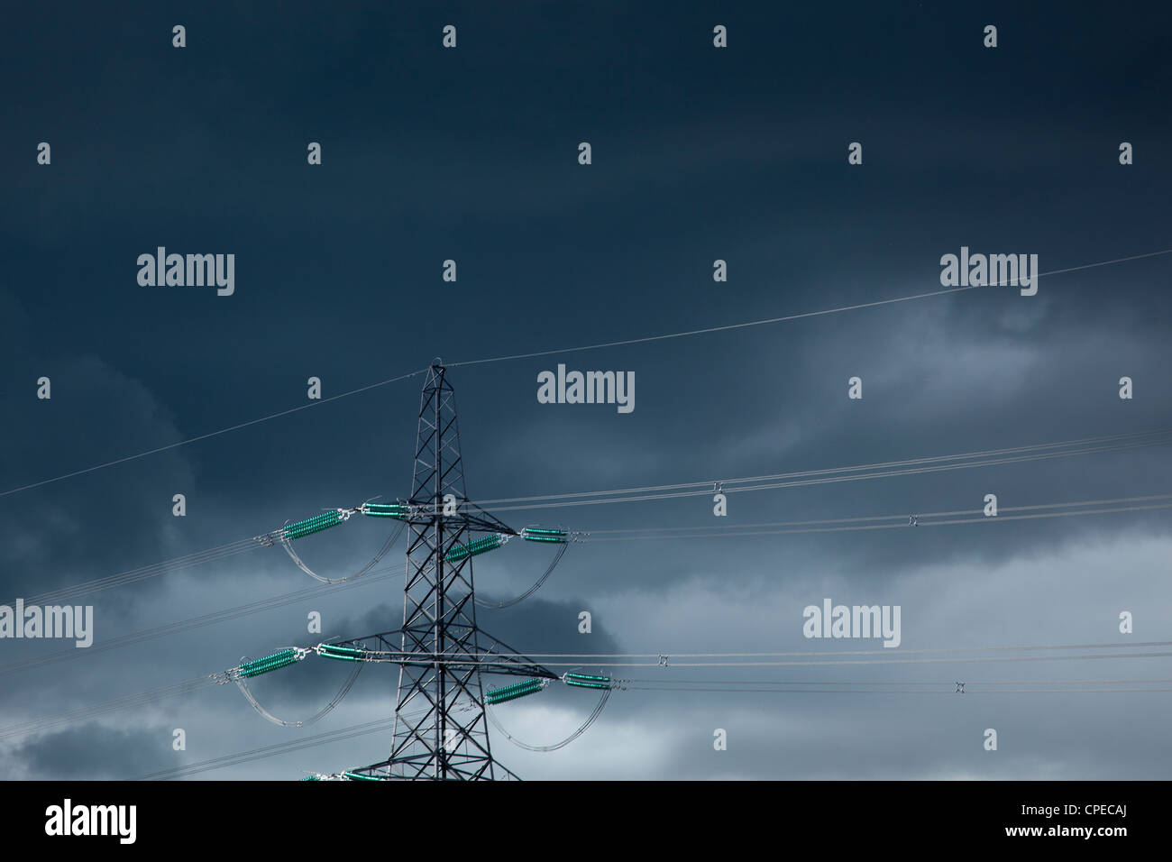 Strommasten und Power Kabel gegen dunklen Gewitterhimmel, England Stockfoto