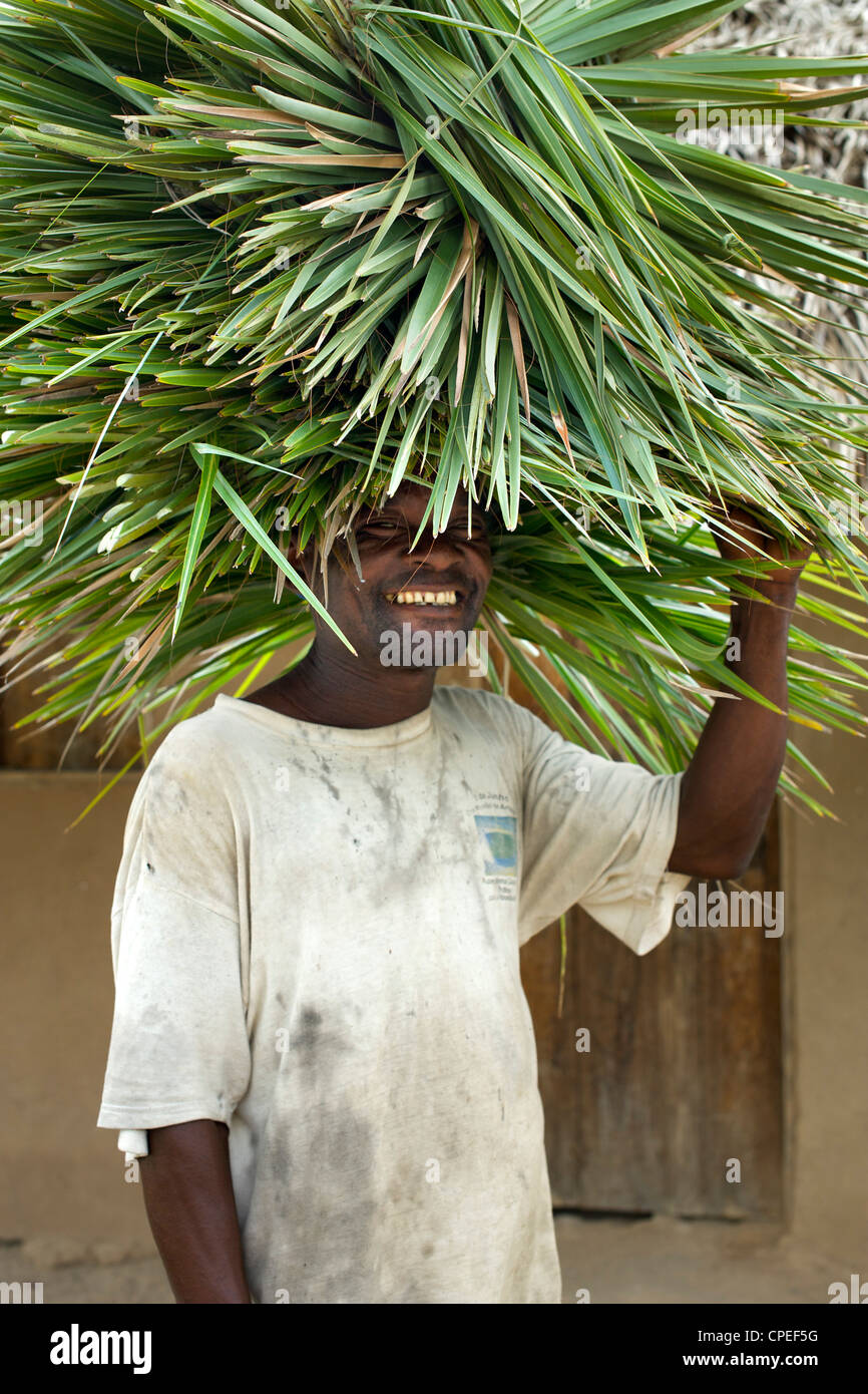 Mann mit Schilf auf seinem Kopf in Guludo Dorf in Quirimbas National Park im Norden Mosambiks. Stockfoto