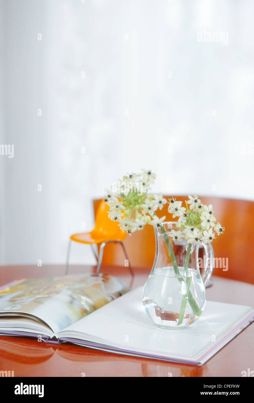 Krug mit Blumen auf offenes Buch Tabelle Stockfoto