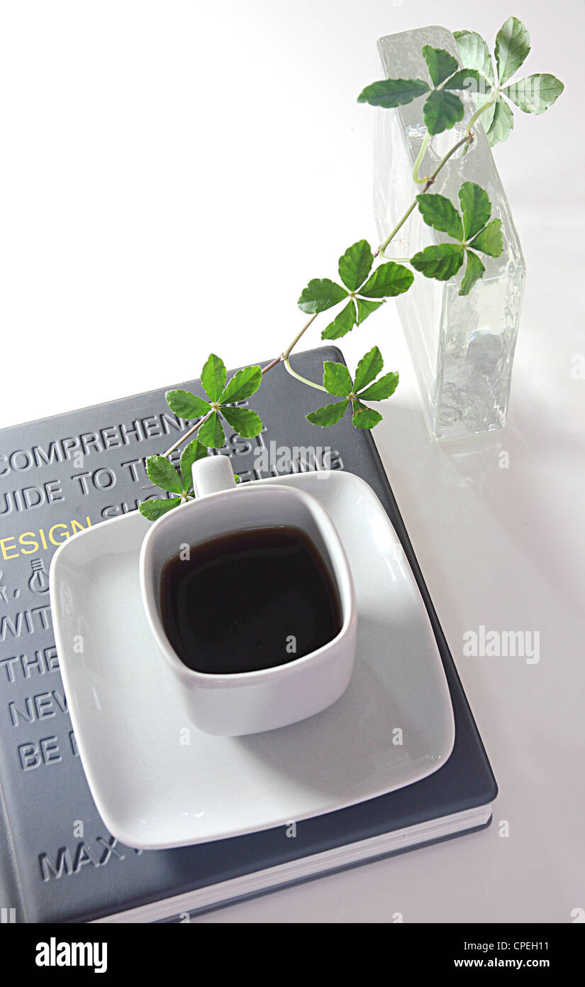 Teetasse und Untertasse, Buch Pflanze Vase auf Tisch Stockfoto