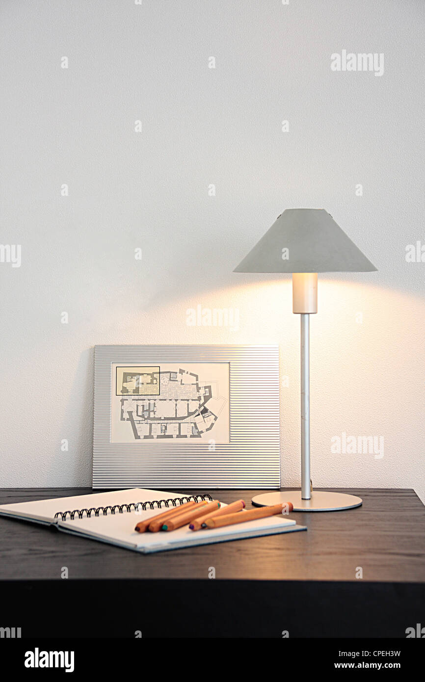 Notebook, Bleistifte und Lampe Set auf Tisch Stockfoto