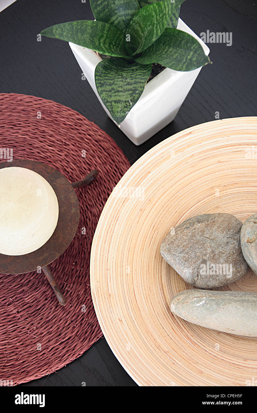 Kiesel im Teller und Zimmerpflanze setzen auf Tisch Stockfoto