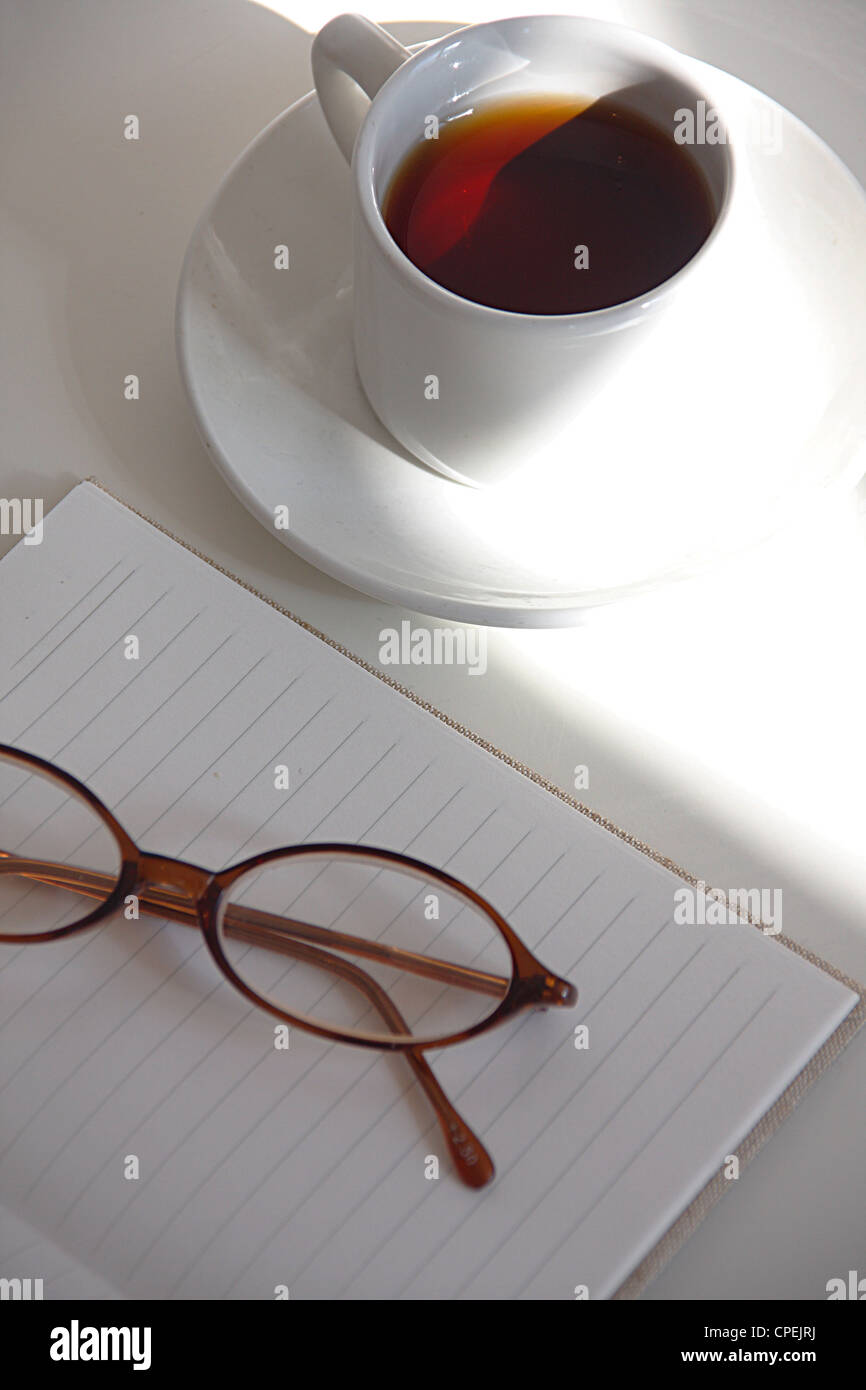Brille auf leeren Notizblock in der Nähe von Tasse Tee Stockfoto