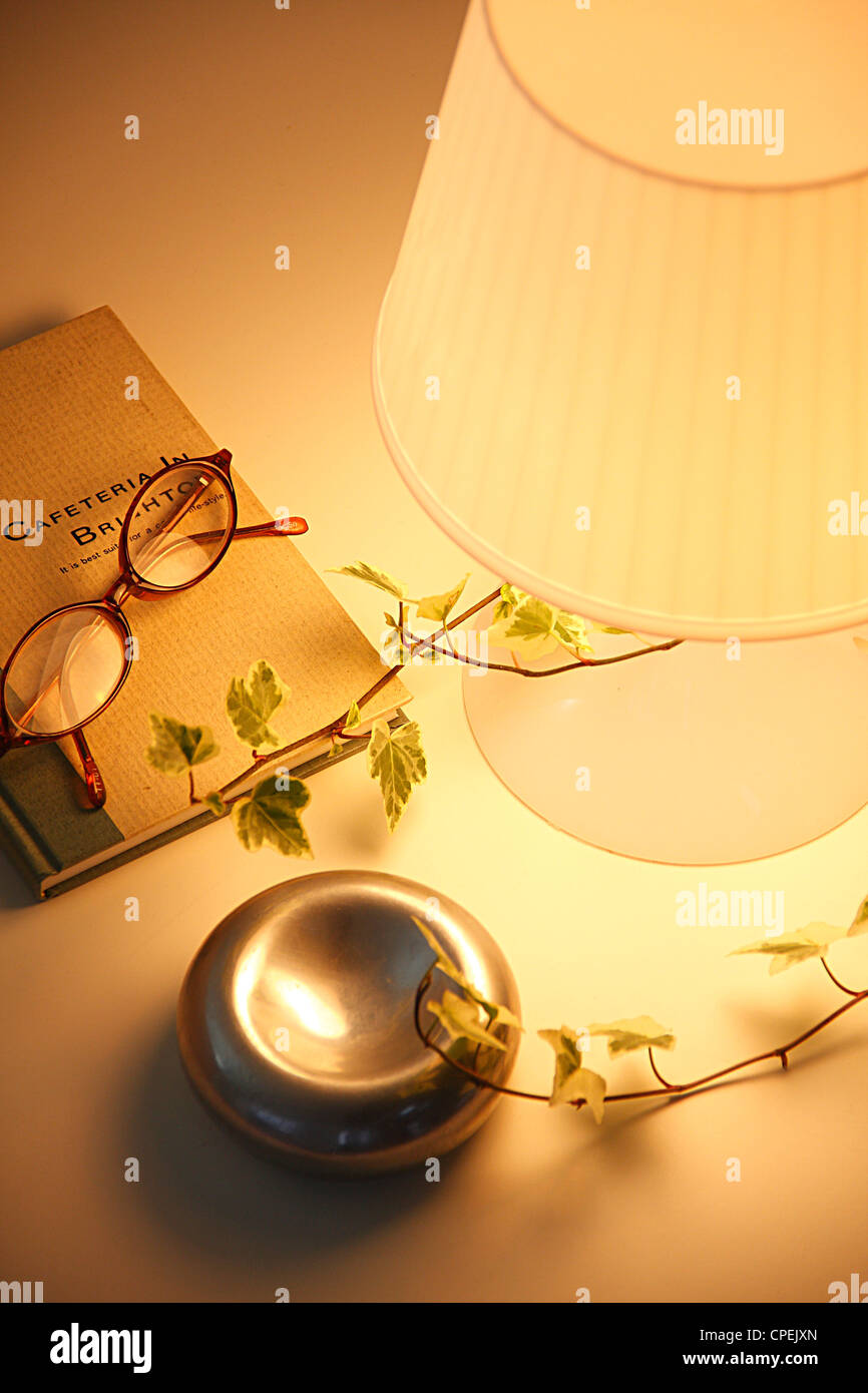 Brille auf Buch mit Aschenbecher und elektrische Lampe Stockfoto