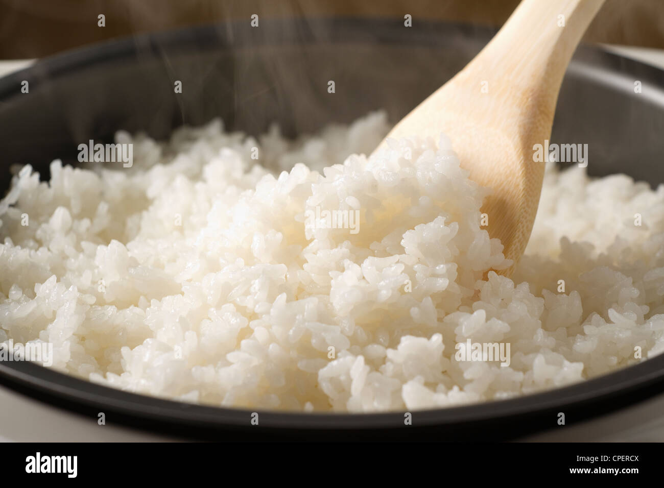 Schüssel mit frischem heißem Reis mit Holz Löffel Stockfoto