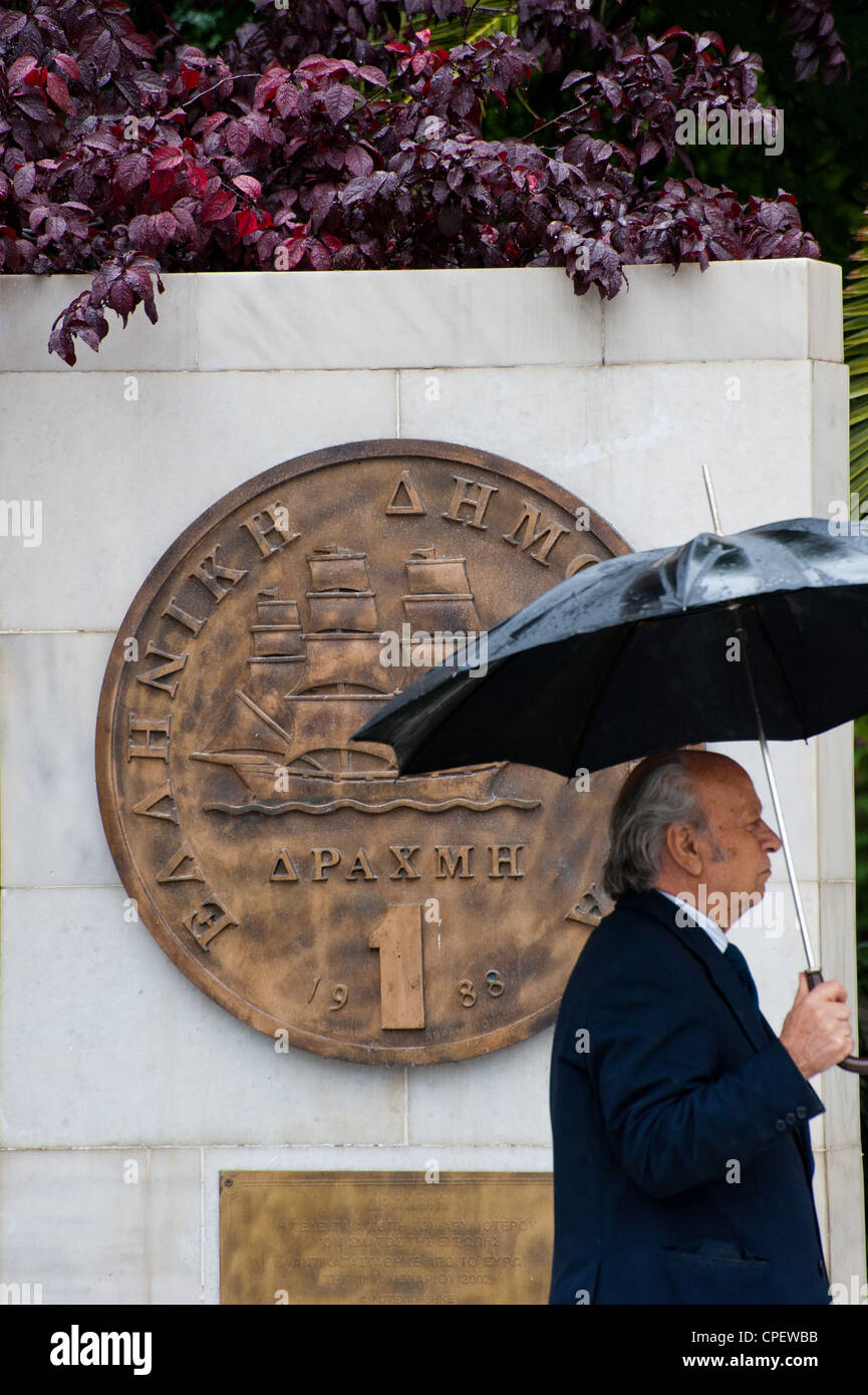 Ein griechischer Mann zu Fuß durch eine Plakette porträtiert eine alte Drachme Münze, die im Jahr 2002 außerhalb Athens City Hall durch den Euro ersetzt wurde Stockfoto