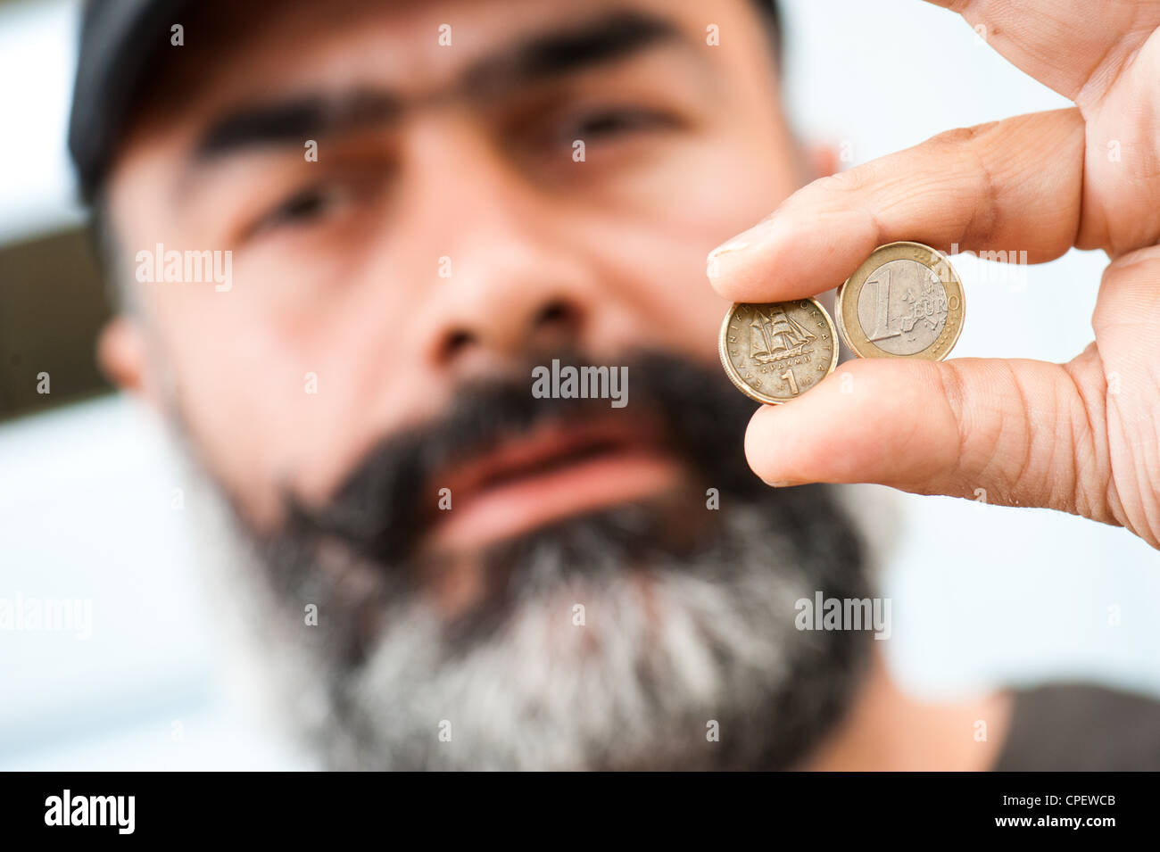 Café-Besitzer Nikos Bourbakis hält eine alte eine Drachme Münze ersetzt durch den Euro im Jahr 2002 und einer griechischen Euro-Münze. Stockfoto