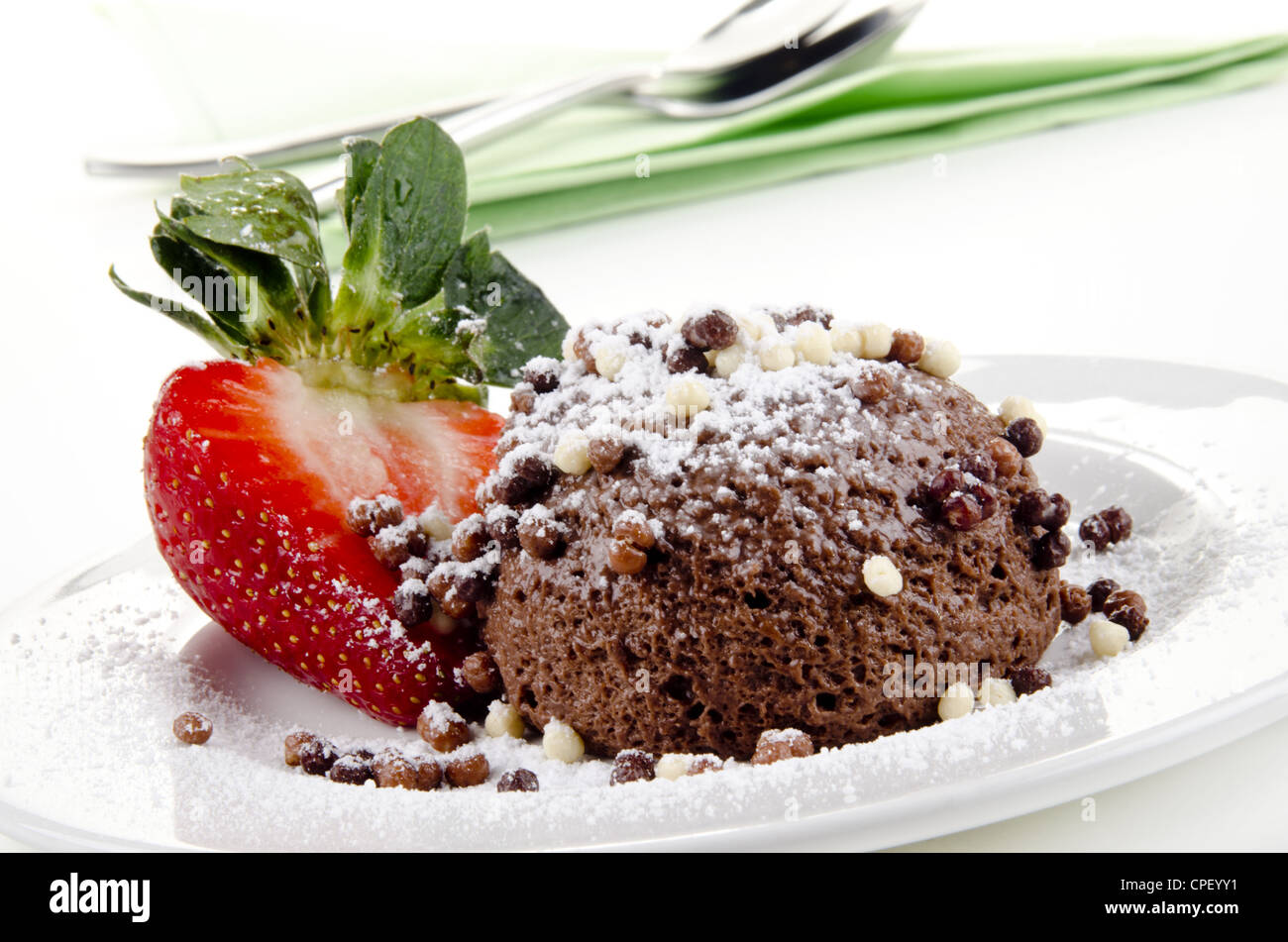Mousse au Chocolat mit Puderzucker, Pulver und Erdbeeren auf einem Teller Stockfoto