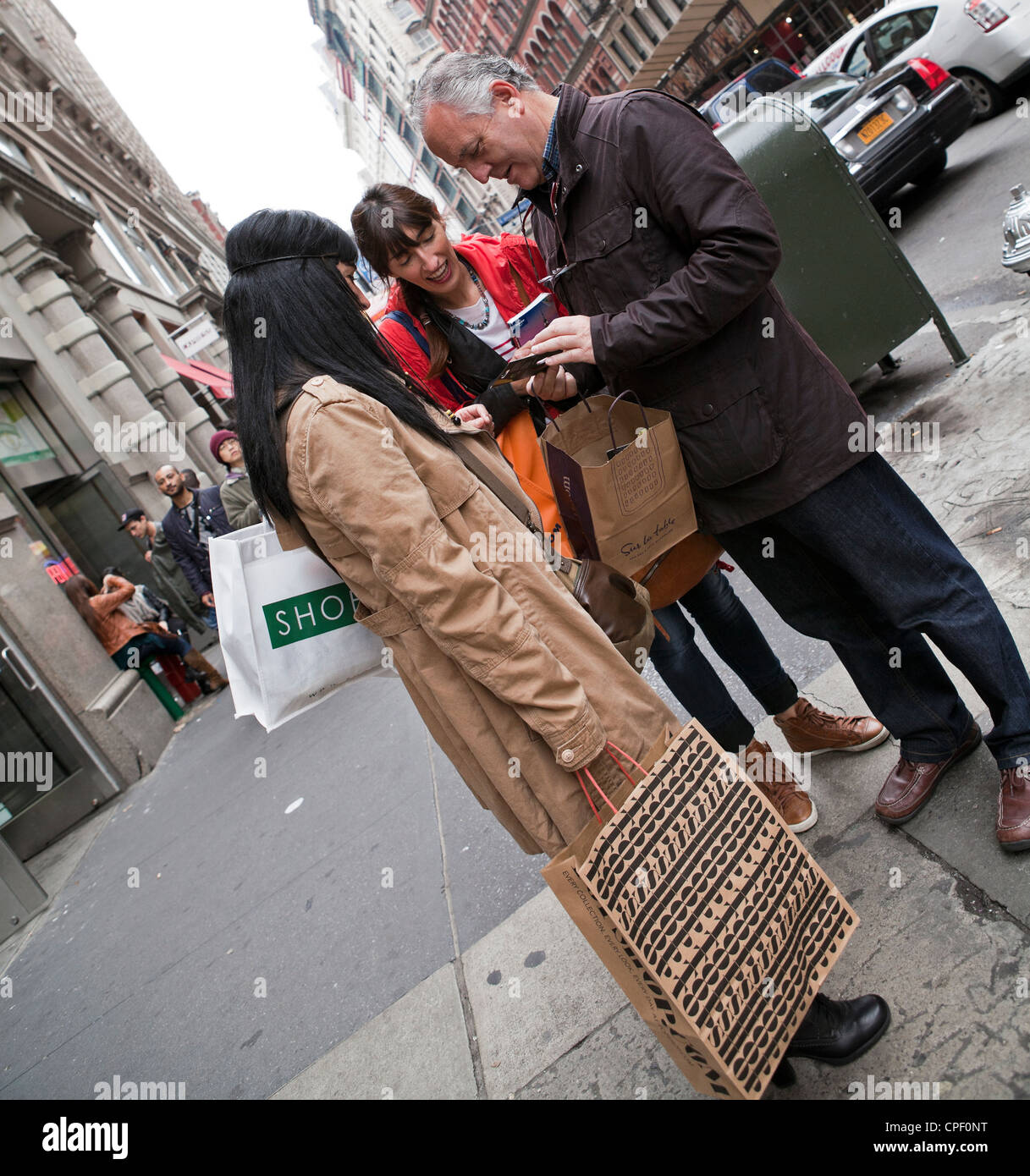 Ein Mann zeigt seine Gefährten seine Einkäufe in New York City. Stockfoto