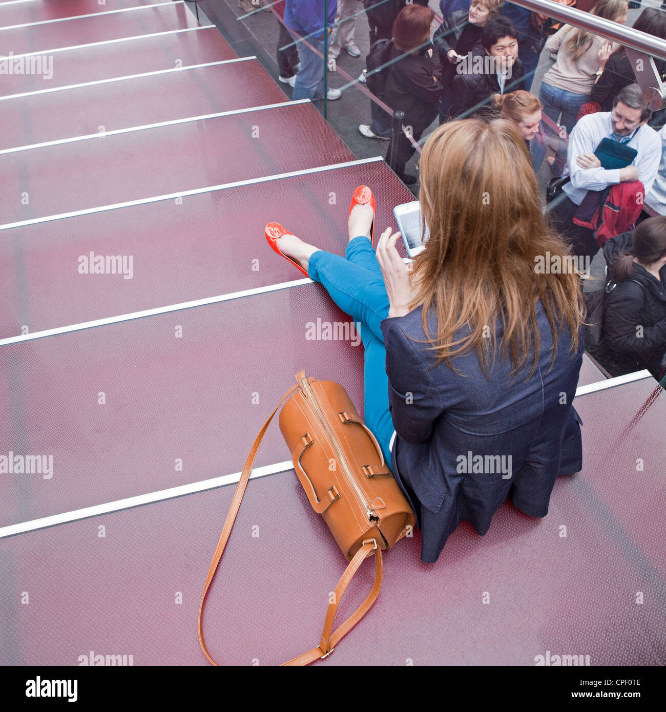 Eine Frau verbringt einen ruhigen Moment mit ihrem Handy vor seinem Eintritt in die Massen auf dem Times Square in New York City. Stockfoto