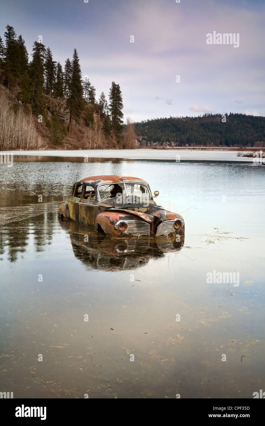 Ein altes antikes Auto sitzt in einem überschwemmten Teich überschwemmt. Stockfoto