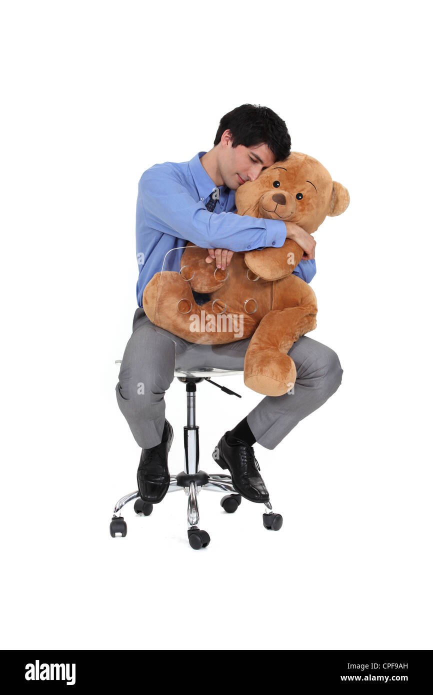 Geschäftsmann saß im Stuhl umarmt Teddybär Stockfoto