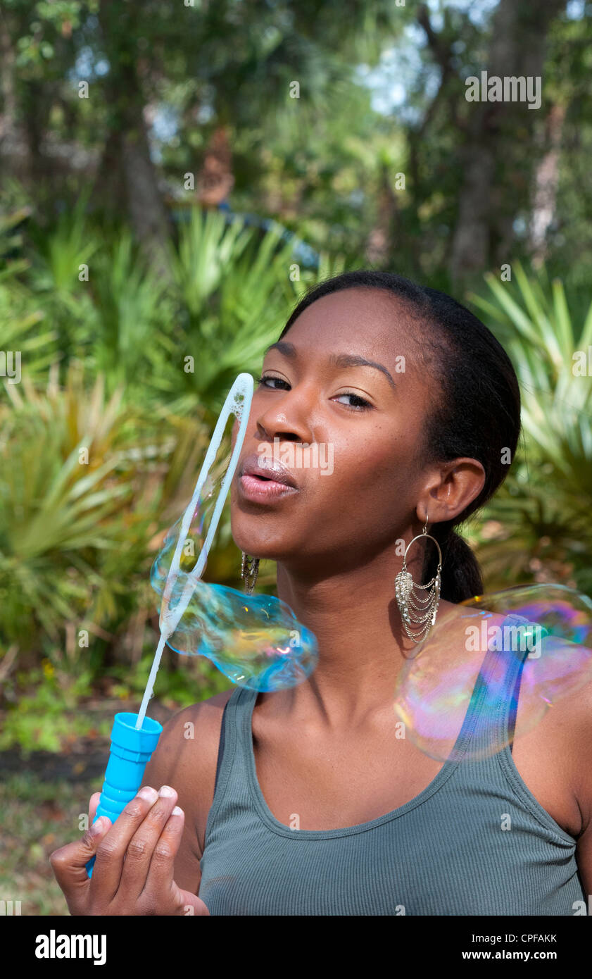 Black African American Mädchen im Alter von 18 blowing Bubbles in Hof im freien lachen Stockfoto