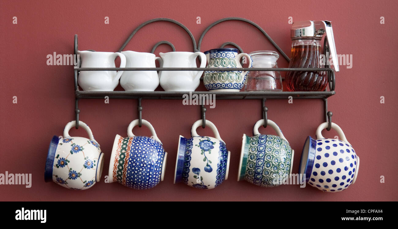 Eine schöne Anordnung der Tassen und Untertassen auf eine Küchenwand. Stockfoto